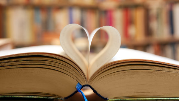 Book page in heart shape with library background
